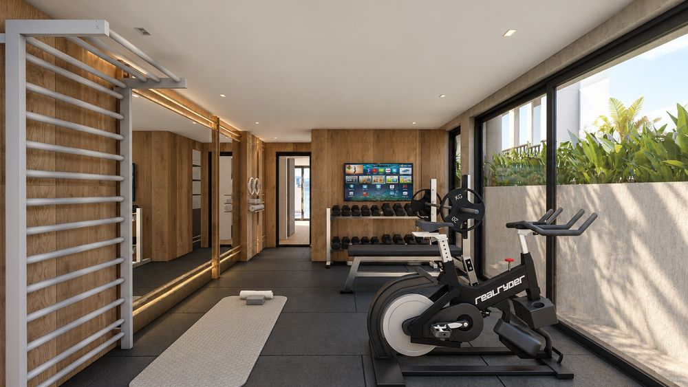 Gimnasio con bicicleta, mancuernas y ventanales hacia la terraza